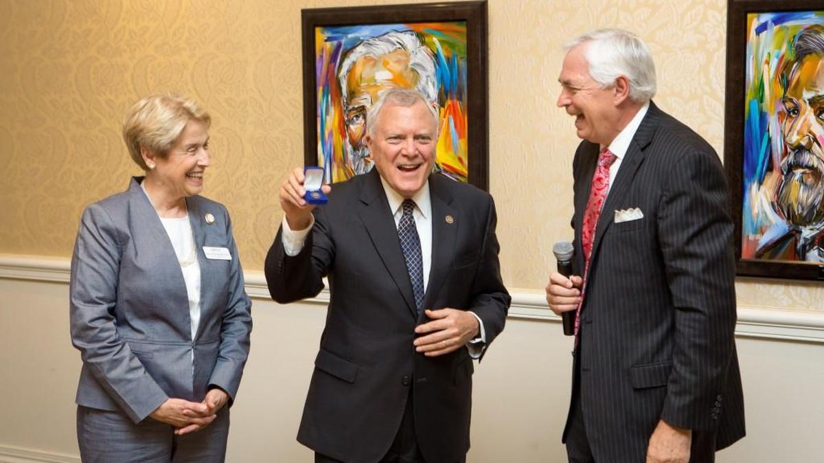 Mercer University President Bill Underwood and Mercer medical school dean Dr. Jean R. Sumner stand with Gov. Nathan Deal as he holds up the pin given to him and each of the Nathan Deal Scholar recipients.