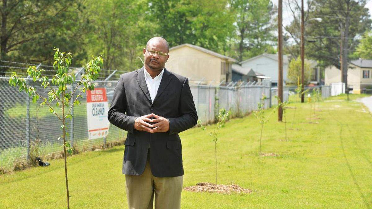 Frank Austin stands in front of the 30 cherry trees planted in Village Green, where the work to reverse blight is ongoging, in this April 2015 photo.