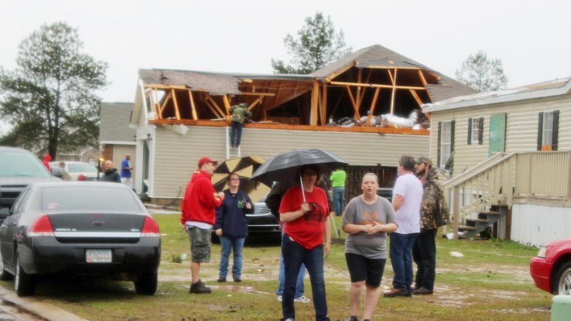 Residents walk by a home in Hidden Creek Circle off Booth Road in Warner Robins that was damaged Saturday by what witnesses said was a tornado.