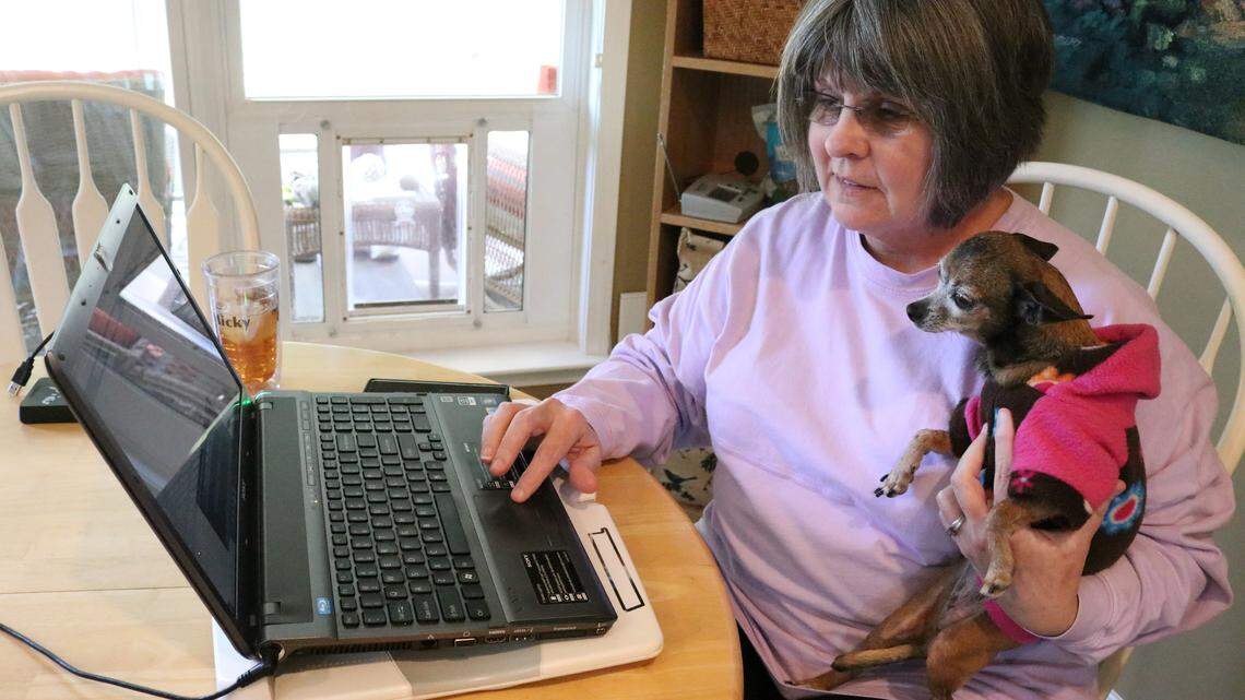 Regi Polk checks her lost pet Facebook page as she holds her dog Macy. She said Macy likes to supervise when she is working on the page.