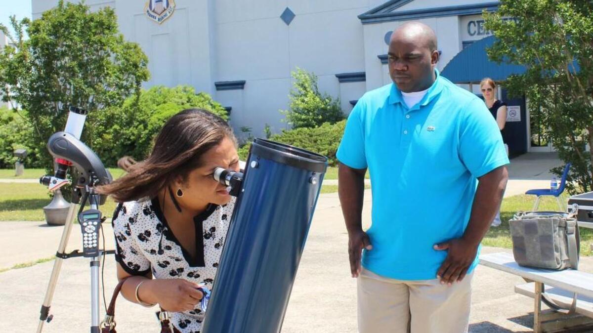 Demetria Harris takes a look at Mercury transiting the sun Monday at the Museum of Aviation as her fiance, Lamarcus Smith, looks on.