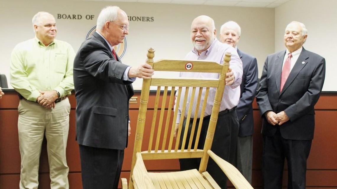 Houston County Commission Chairman Tommy Stalnaker, left, presents Jimmy Autry with a rocking chair as a retirement gift.
