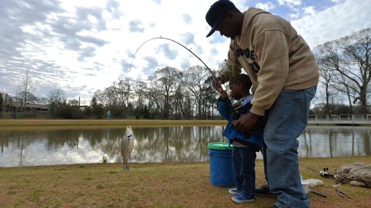 Benny Sandifer, right, helps his son, Deshaun Smith, land a striped bass at the Go Fish Education Center in 2014.