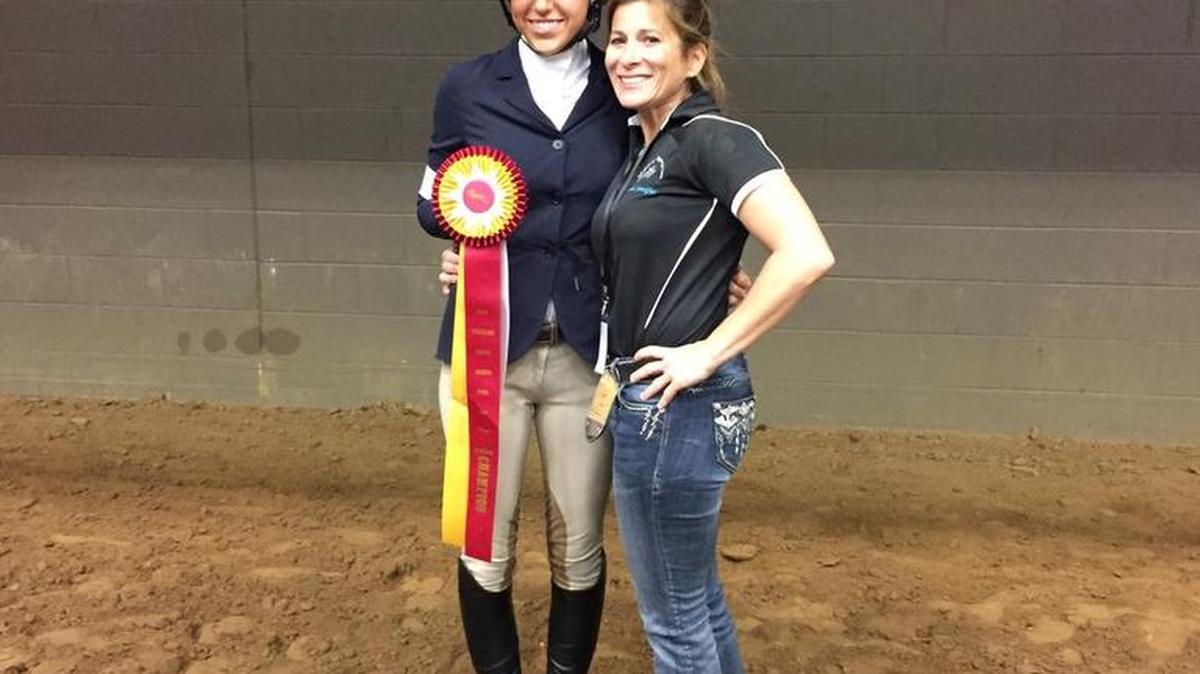 Olivia Oney holds her second-place ribbon while standing next to trainer Jennifer Mastronardi.