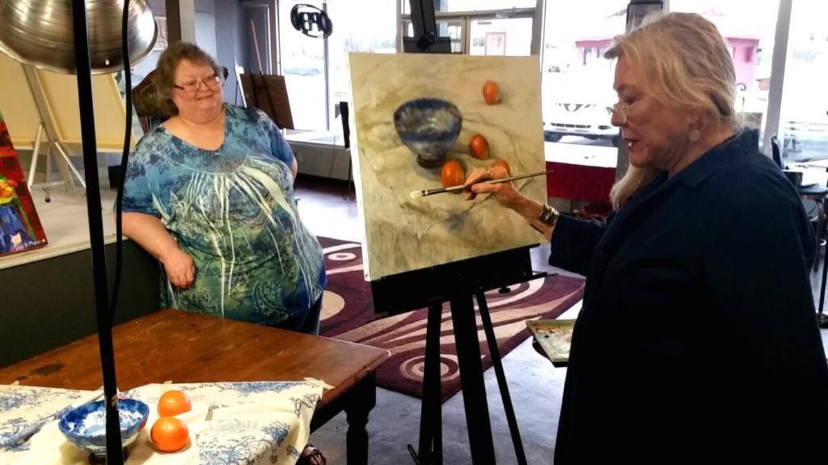 Artist and gallery director Leslie Hoops-Wallace, left, talks with Fine Art Society of Middle Georgia founder and instructor Deanna Griffin as she works on a still life scene used in her oil painting class at the FAS gallery.