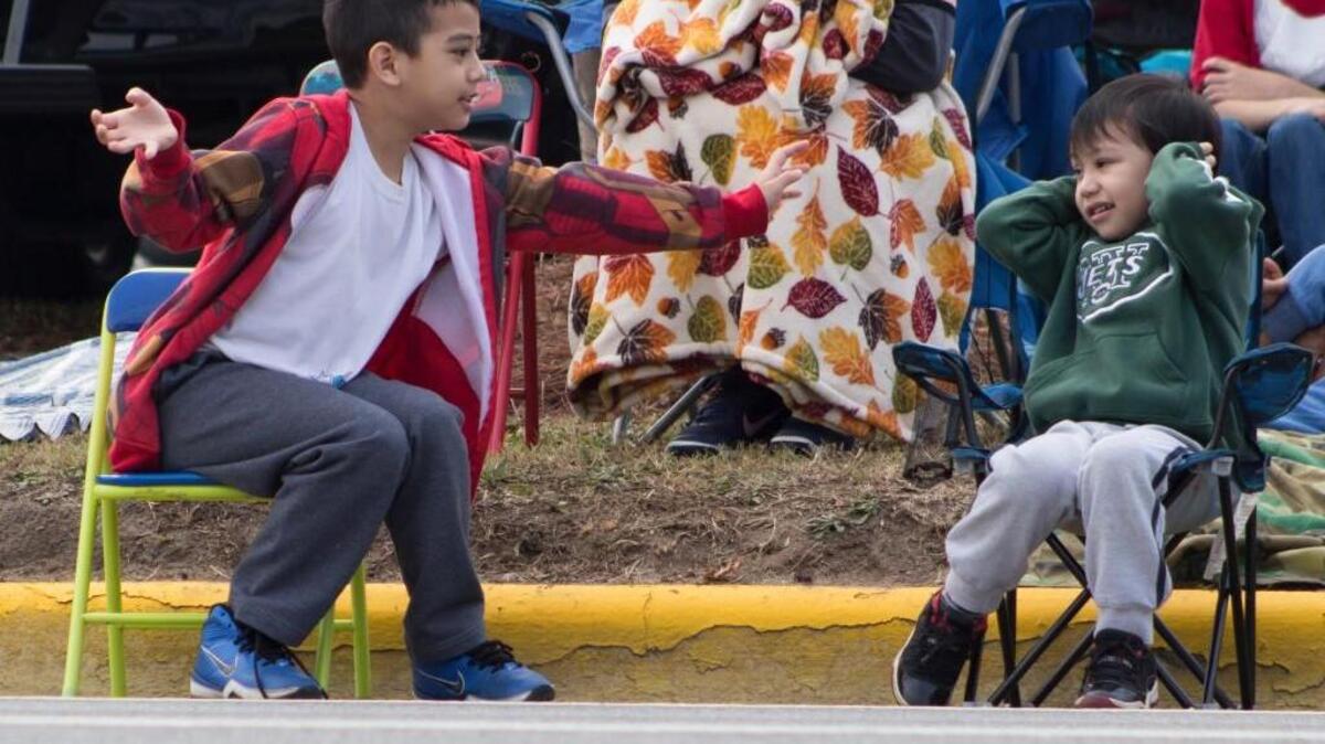 Mark Strickland, left, tries to get his little brother, Caleb, to wave at the floats while Caleb holds his ears as a loud truck drives by at the Robins Regional Christmas Parade on Saturday.