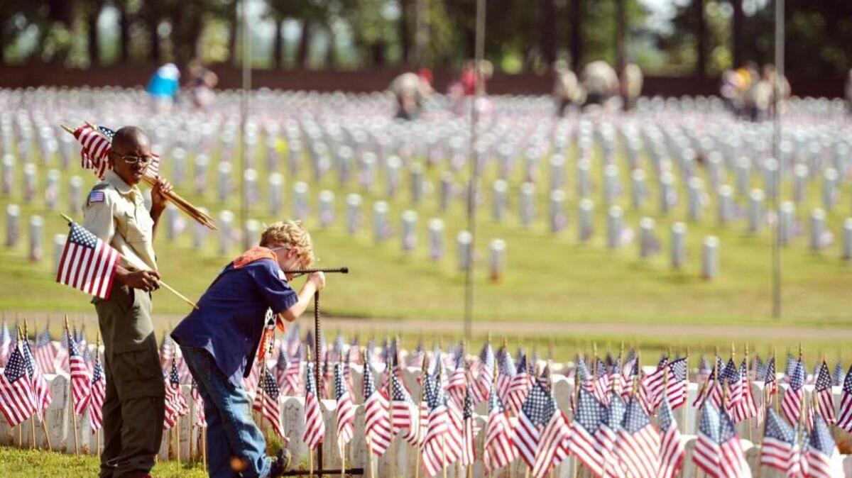Zahkee Thomas, left ,with Boy Scout Troop 410, and Thomas Jackson, with Cub Scout Pack 410, place flags at Andersonville National Cemetery for Memorial Day weekend observances in 2014.