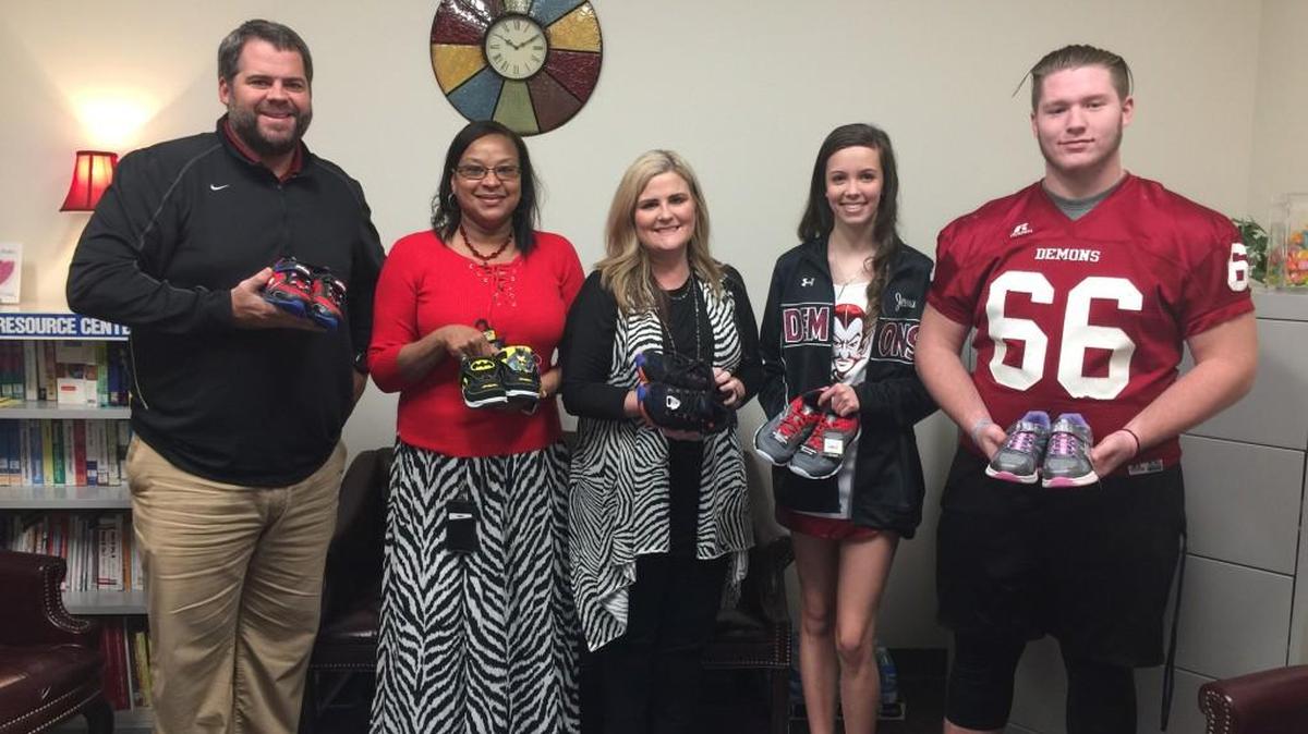 Warner Robins High School football coach Mike Chastain, C.B. Watson Primary School counselor Sheila Kendrick, C.B. Watson Principal Alicia Conner, Warner Robins High football player Dillon Braunstein and Warner Robins High cheerleader Jenna Stork show off some of the shoes collected by the Warner Robins High football team and cheerleaders.
