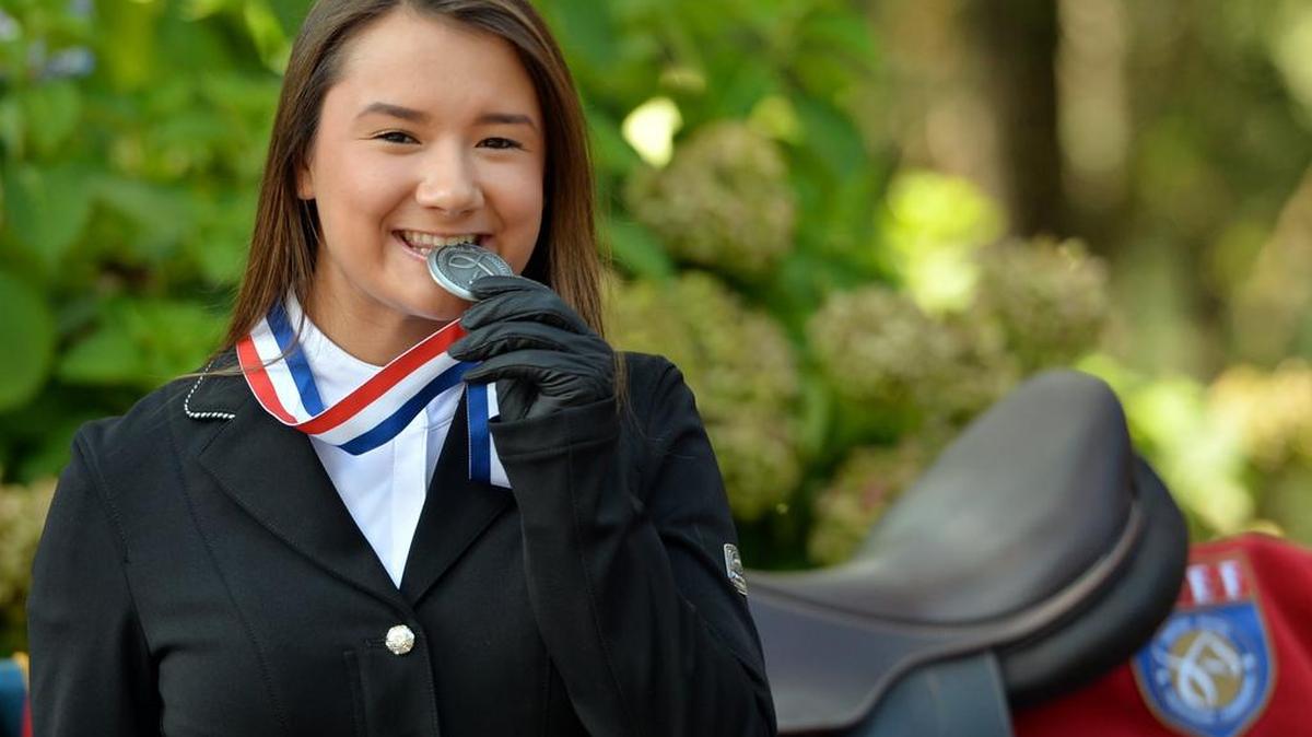 Nadia Rosenbaum takes a bite of the silver medal she won competing in the United States Equestrian Federation Pony Finals recently in Lexington, Kentucky.