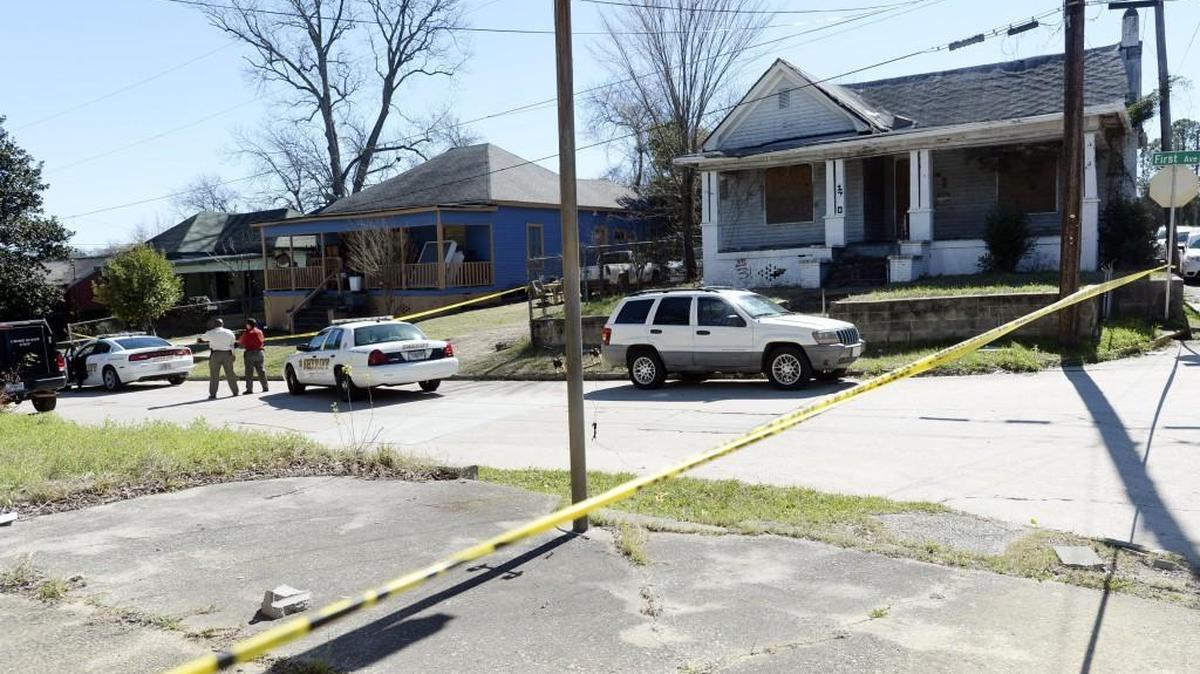 Bibb Sheriff's deputies wait outside a home on First Ave. for a search warrant after discovering a body Thursday morning. They had not identified the person they found pending notification of relatives.