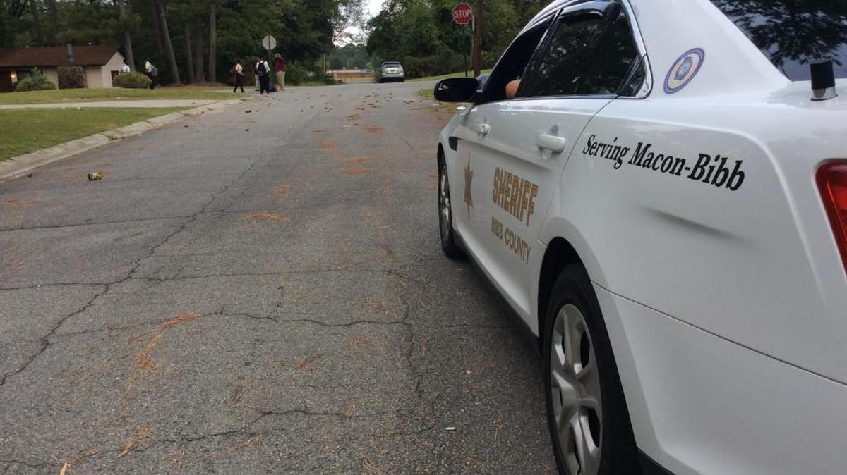 A Bibb County sheriff’s deputy watches the bus stop Wednesday morning on Elkan Avenue and Dapleton Drive after a mother reported her child was chased by clowns the morning before.