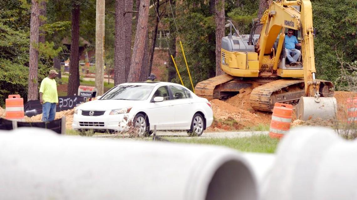 Contractors fill in a storm drainage ditch along Forest Hill Road as drainage pipe cover the front yard of a home on Normandy Road on 9/02/2015.