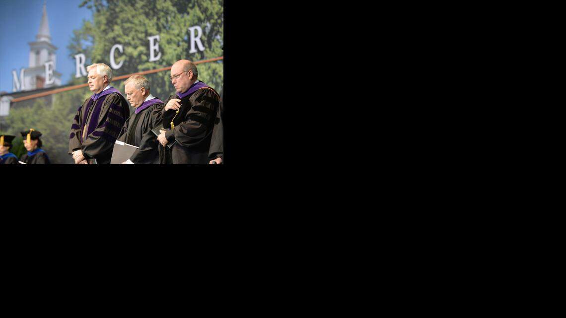 Mercer University President Bill Underwood, Gov. Nathan Deal, and Richard Schneider bow in prayer during the invocation for the Macon Commencement May 10, 2014.