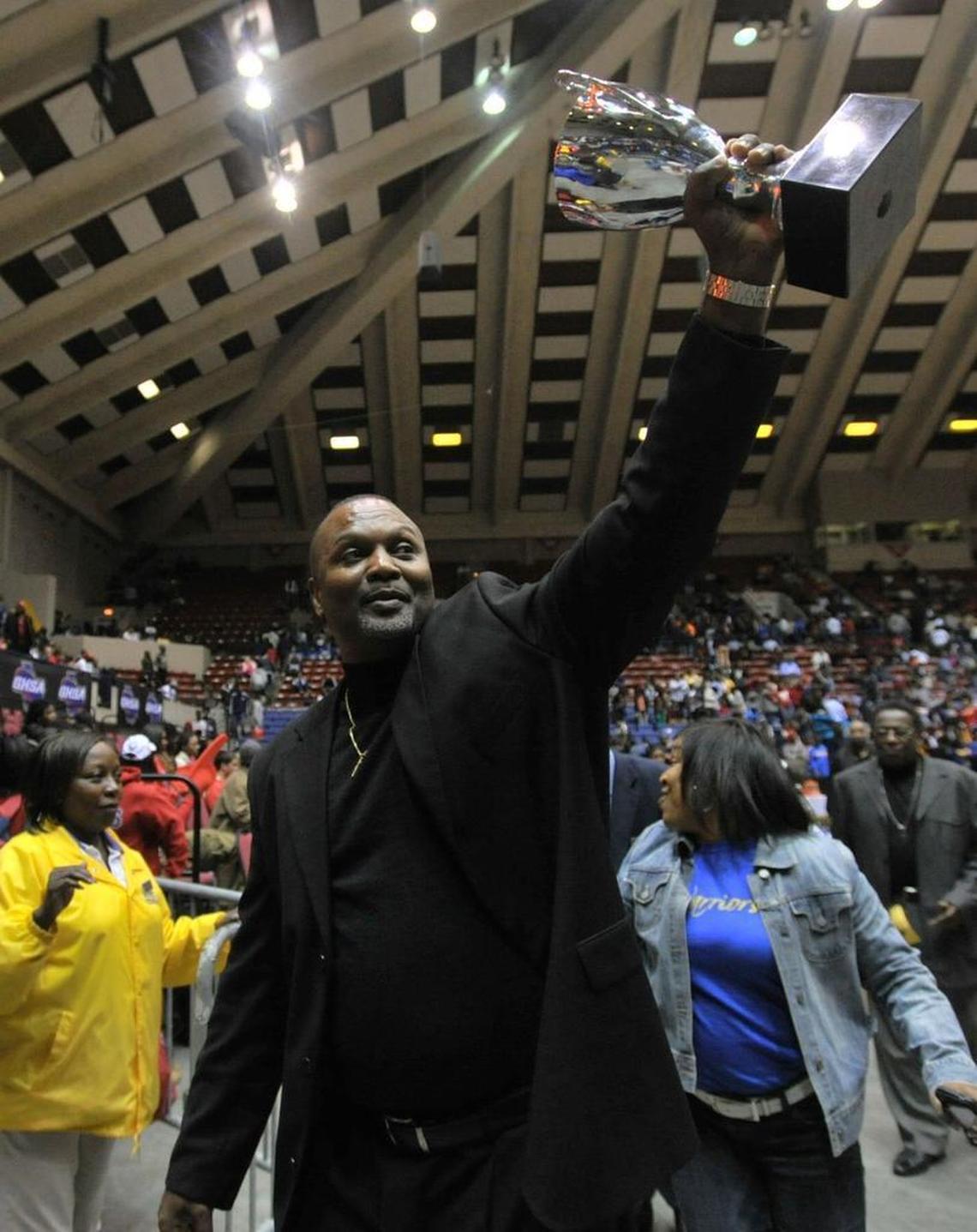 Wilkinson County coach Aaron Geter shows fans the trophy as he walks off the court with his team. Wilkinson beat Wilcox, 53-49 to win the 2013 GHSA Class A boys state championship.