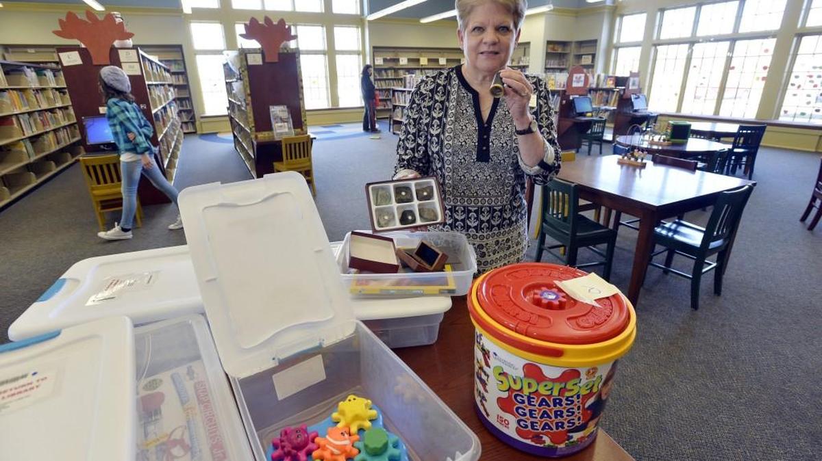 Nancy Granger, Centerville Library branch manager, holds moon rocks and a a device to view them, one of the more popular STEAM kits at the library, on Dec. 29, 2016.
