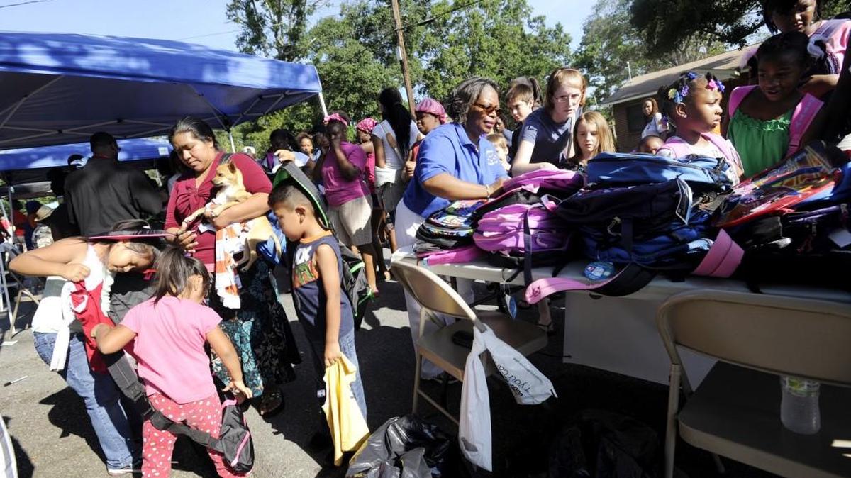 Children grab free backpacks during the 2013 Back-to-School Bash at Cam Campbell Homes in Warner Robins.