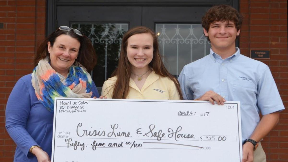 Eleanor Anderson, center, and Benjamin Smith, right, present Dee Sims, executive director of Crisis Line and Safe House of Central Georgia, with a check for the money they raised from a cellphone drive.