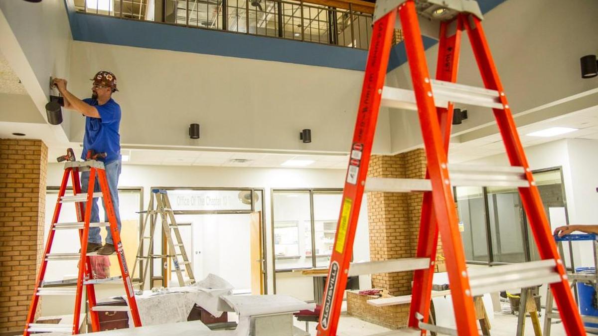 Electrician Rick Sherrill installs a light fixture in the lobby of the former Sears building at the corner of Third Street and Riverside Drive in this 2015 file photo.
