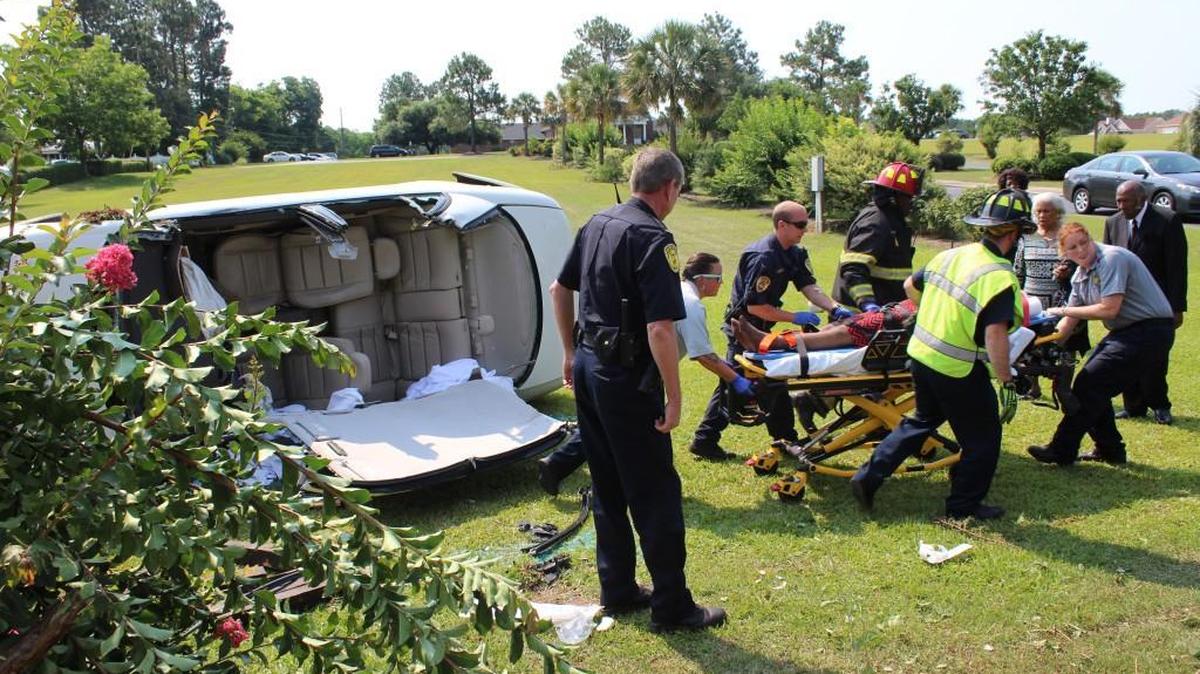 Rescue workers move Mattie Henley toward an ambulance after she had to be freed from her overturned vehicle Sunday in front of her church.