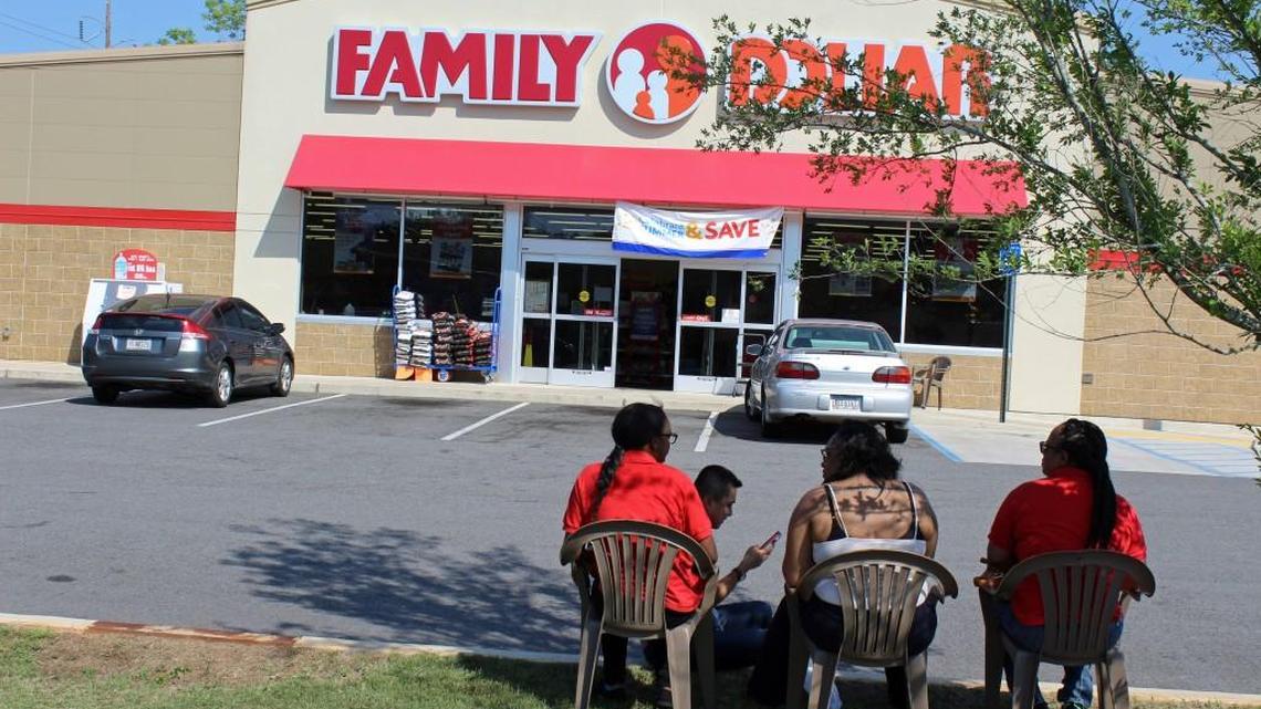 Family Dollar employees wait outside following an armed robbery Tuesday while police investigators process the scene.
