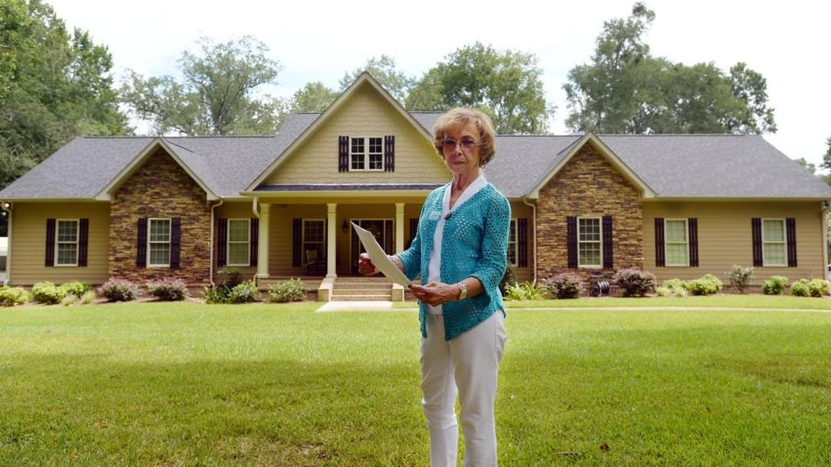 Lola Williams stands in front of her Beaver Ridge Circle home that was comfortable to live in before a 2014 fire destroyed it. After she and her husband rebuilt it, their property taxes more than doubled.