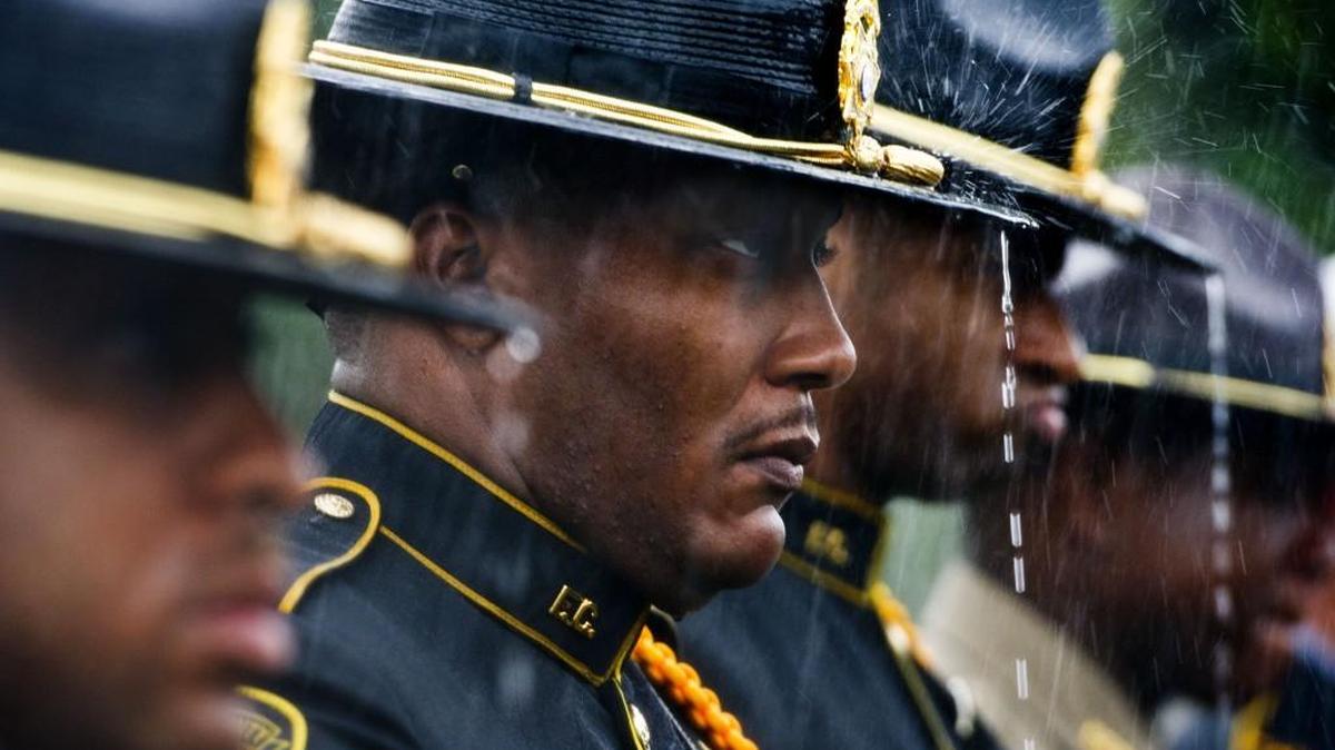 Fulton County honor guard members Lt. Damien Butler, Sgt. Randell Lattimor and Deputy Rashad Wheeler stand at attention in the rain at the graveside service for Eastman police officer Tim Smith in 2016.
