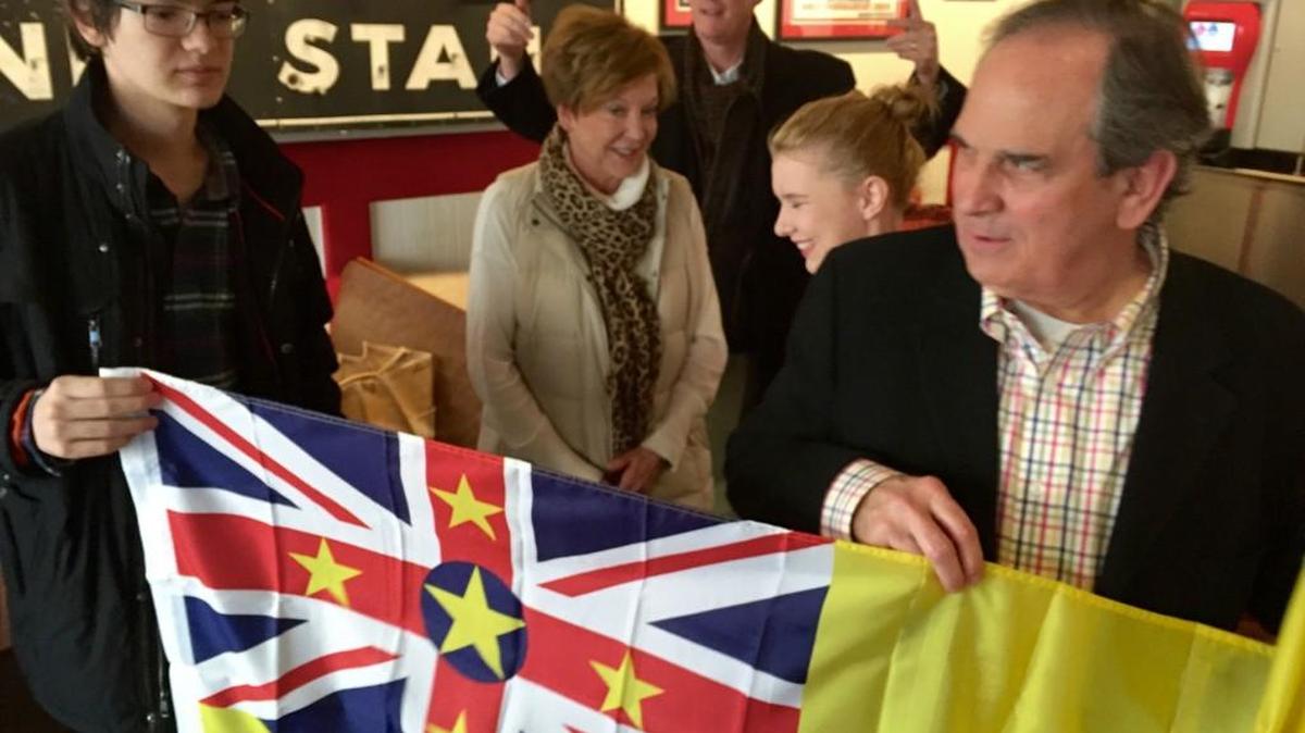 Alex Smith and Macon-Bibb County Mayor Robert Reichert unfold a Niue flag Saturday at the Nu-Way in Mercer Village.