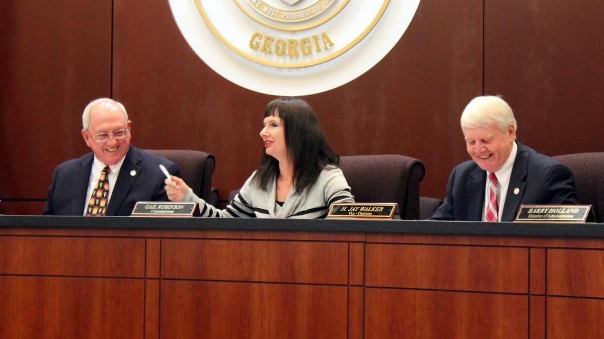 Houston County Commission Chairman Tommy Stalnaker, left, and Commissioner Jay Walker, right, laugh after appointing Commissioner Gail Robinson as the board’s vice chairman for the coming year.