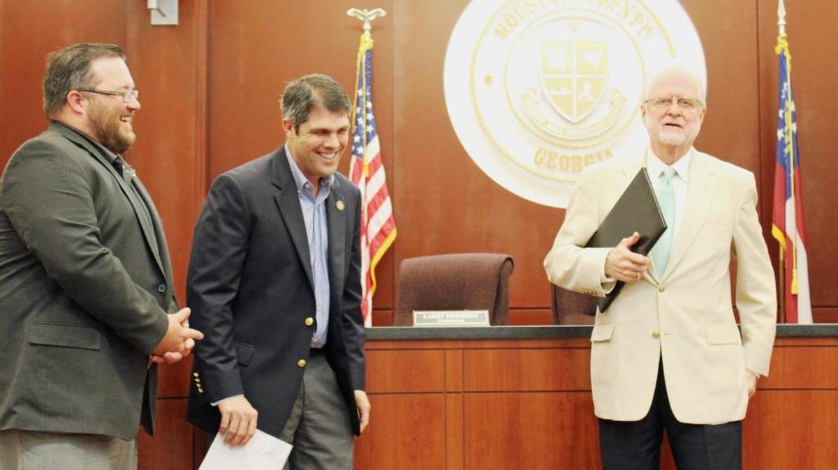 Houston County state representatives Heath Clark, left, and Shaw Blackmon laugh as Tony Robbins tells a story about his service on the Board of Elections at Tuesday’s county commission meeting.