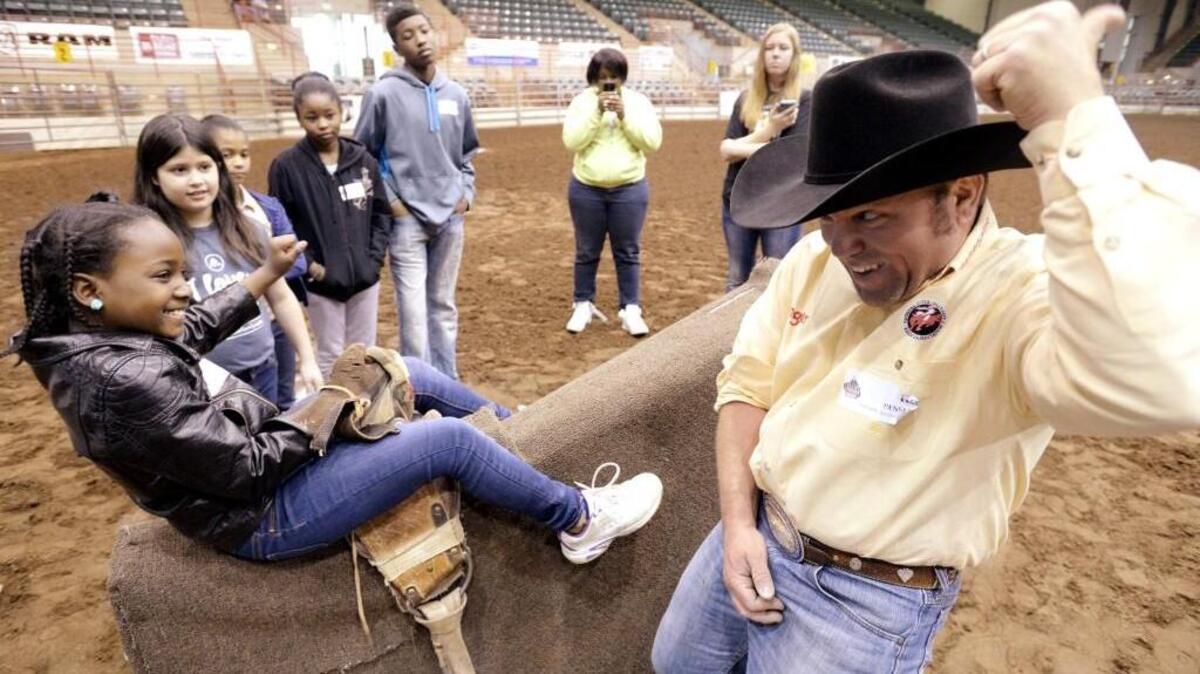 Tim Hensley of Butler shows Tracy Toney, 7, of Monroe where to place her arm while teaching the fundamentals of bareback bronc riding during a Professional Rodeo Cowboy Association "Roughstock Rodeo Camp" at the Georgia National Fairgrounds in Febuary, 2016.