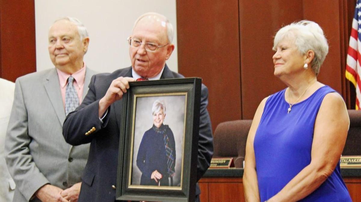 Houston County Commission Chairman Tommy Stalnaker shows a portrait of former State Court Clerk Sissi Gann, right, that will hang in the State Court building.