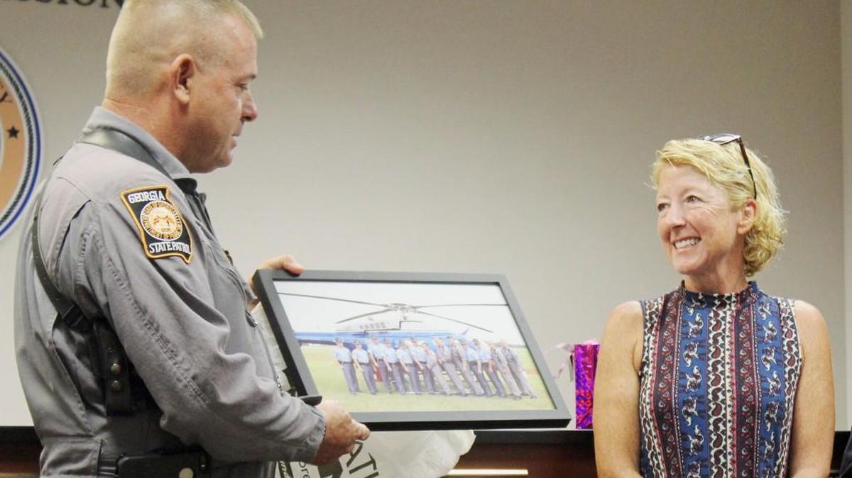 Sgt. Hamilton Halford, hangar commander of the Georgia State Patrol helicopter unit based at the Perry-Houston County Airport. presents Patsy Goff with a photo taken at the opening of the hangar. Goff recently retired as manager of the airport.