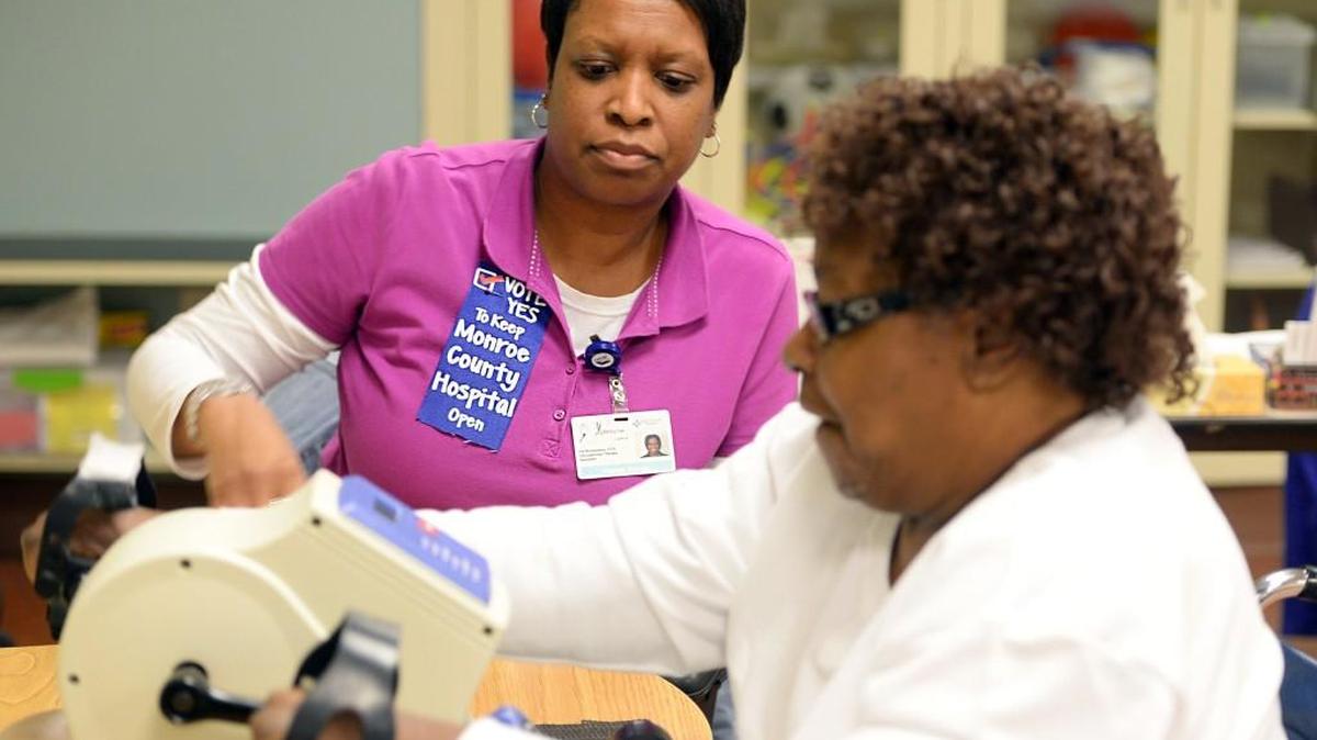 Occupational therapy assistant Iris Richardson, left, wears a veritable billboard with her choice in the upcoming referendum to fund the Monroe County Hospital, helps Elizabeth Watts of Forsyth with her exercise on Jan. 27, 2017.