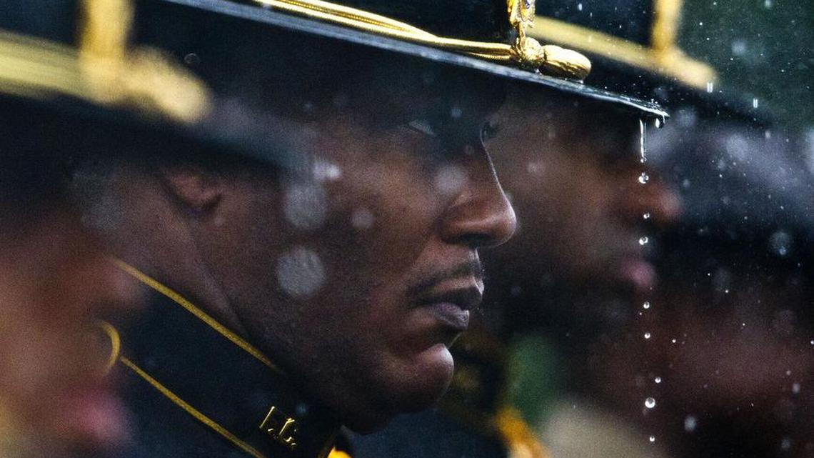 Rain drips from Fulton County Sheriff’s Office honor guard team member Sgt. Randell Lattimore's campaign hat as he stands at attention at the graveside service for Eastman police officer Tim Smith on Thursday.