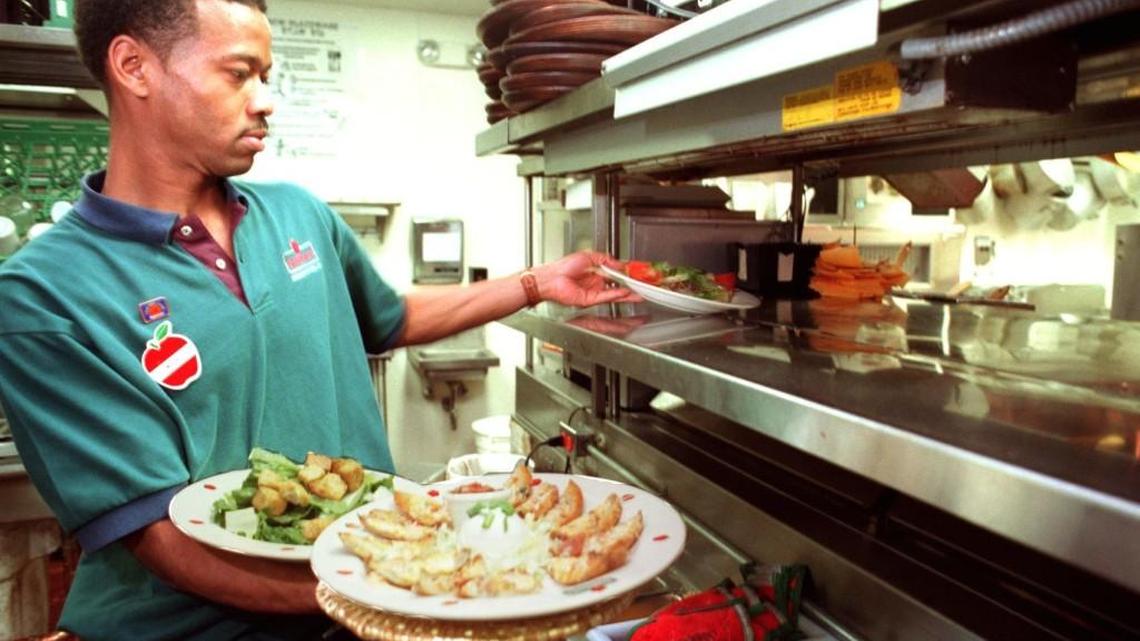 William Neal, a waiter at Applebee's on Riverside Drive, picks up a order in the kitchen. The restaurant is offering free meals for kids on July 4th.