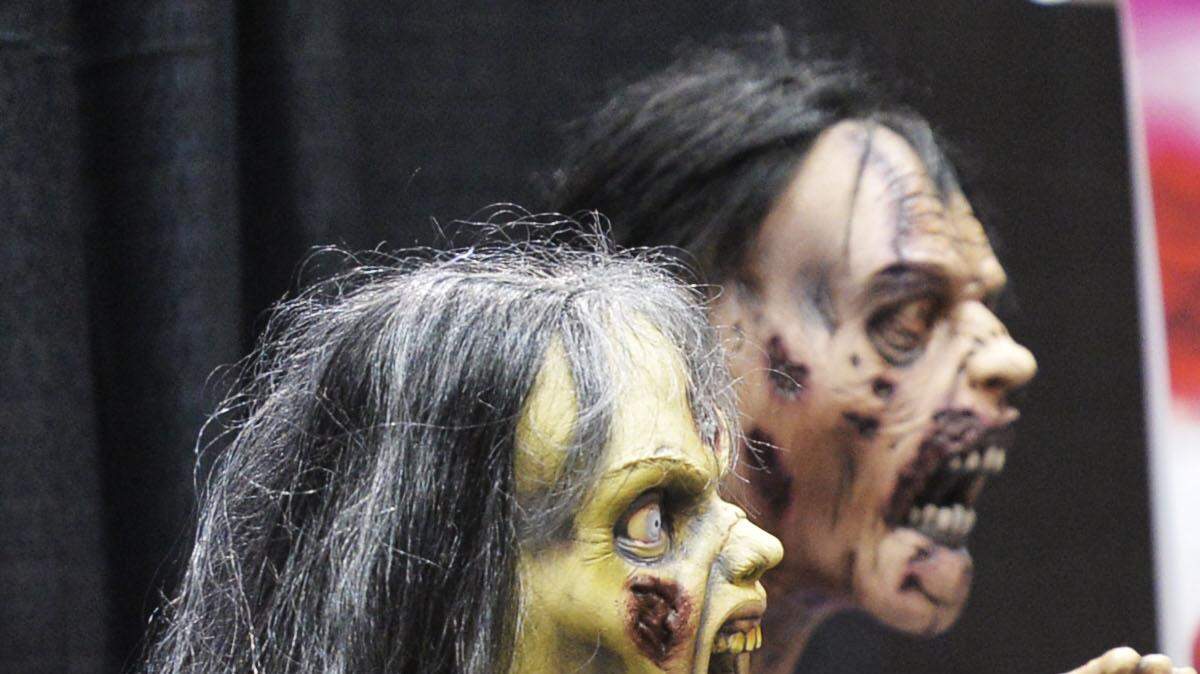 Jared Harnist snacks amongst zombies March 16, 2014, as he and his uncle, Joey Harnist promoted their game, Soul Survivor, at the Middle Georgia Comic Convention in Macon.