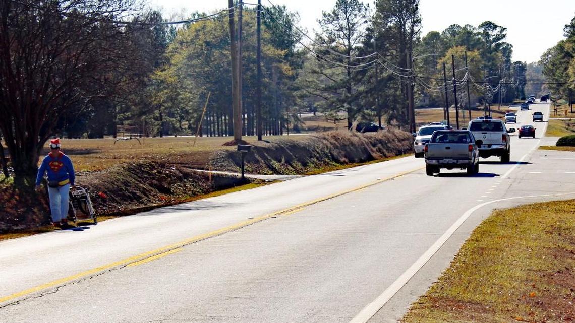 A man walks along Houston Lake Road in Perry on Wednesday. The proposed Houston County special purpose sales tax includes $3.5 million for the widening of the road from two lanes to three with sidewalks.