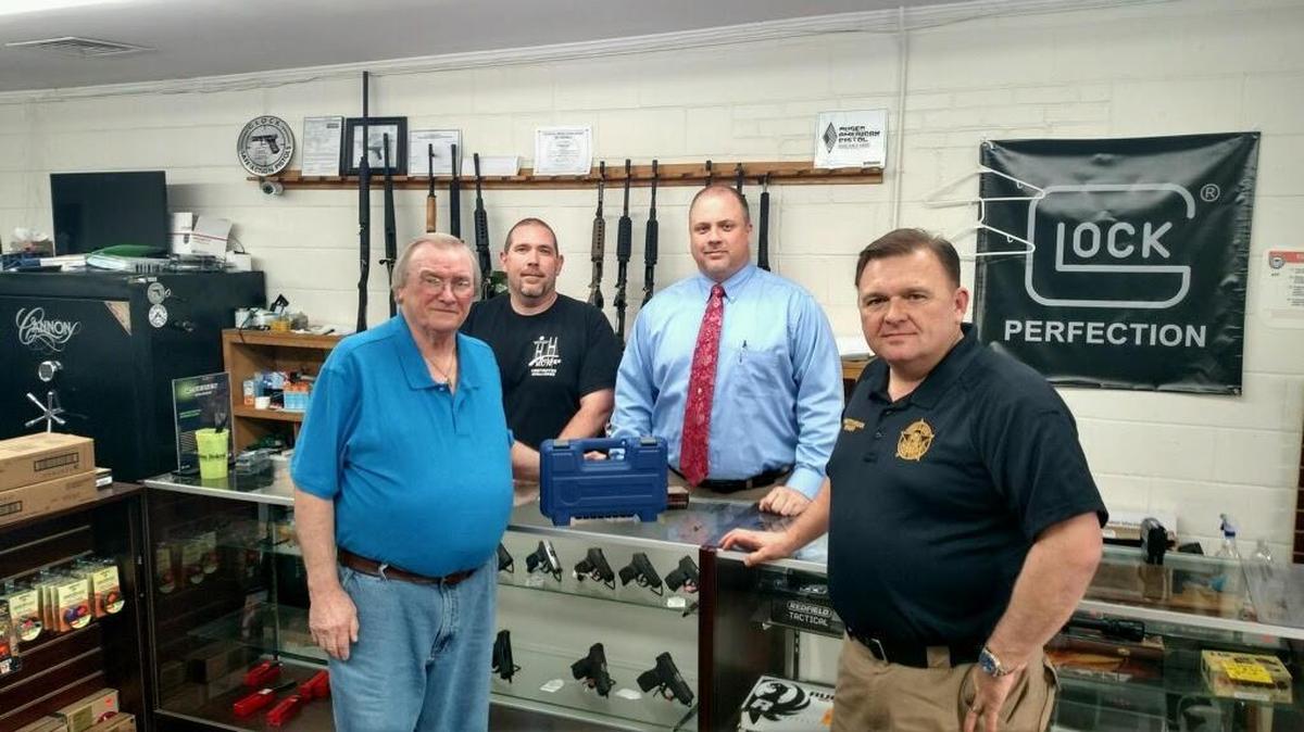Billy Harrell, left, picks up a new .38 Smith & Wesson from CL Defense owners Lamar Marshall and Chris Ellis, pictured Wednesday at the store in McRae with Telfair County Sheriff Chris Steverson, right.