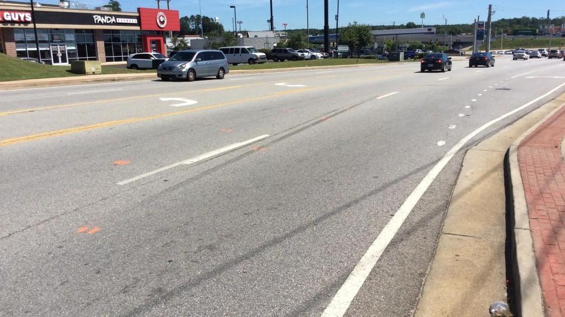 The Bibb County sheriff’s fatality investigator’s orange paint on the pavement shows where a car veered and struck an unidentified man just past the entrance to the Starbucks on Tom Hill Senior Boulevard.