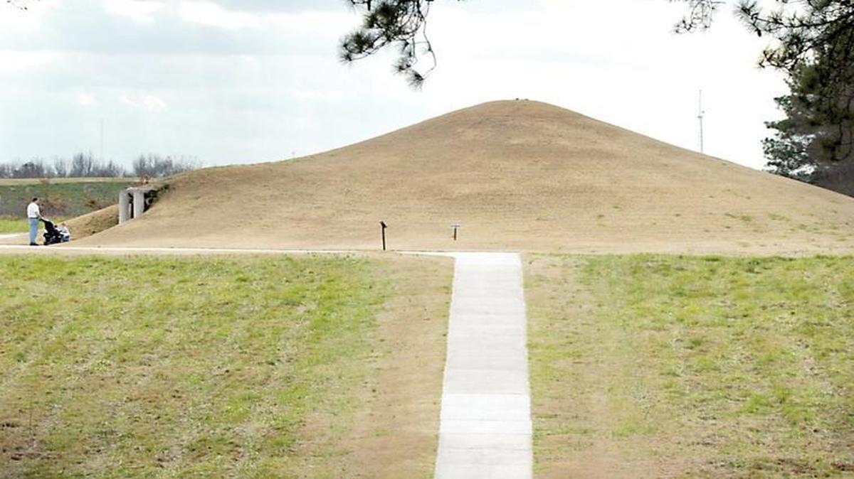 People walk towards mounds after listening to storyteller Curly Bear Wagner, who tells a story of the Lewis and Clark expedition from the Blackfoot point of view at Ocmulgee National Monument.
