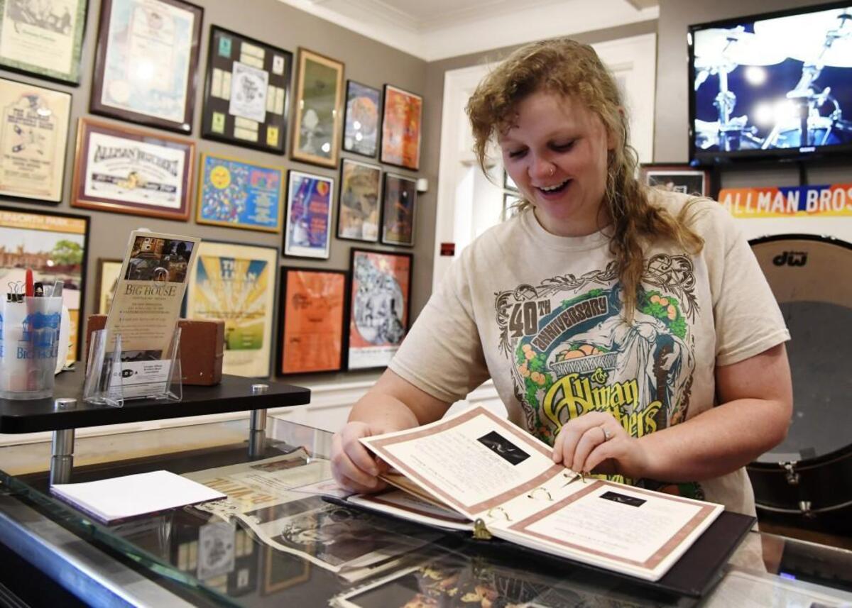 Big House Museum marketing director and office manager Maggie Johnson flips through the Gregg Allman funeral guest book people signed last Saturday and Sunday.