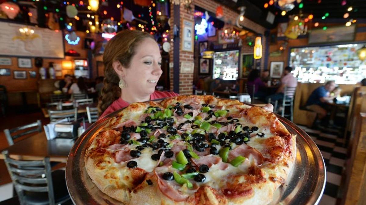Carrie Sullivan serves up a green pepper, black olive and ham pizza at Ingleside Village Pizza where they are celebrated their 25th anniversary in July in this Telegraph file photo.