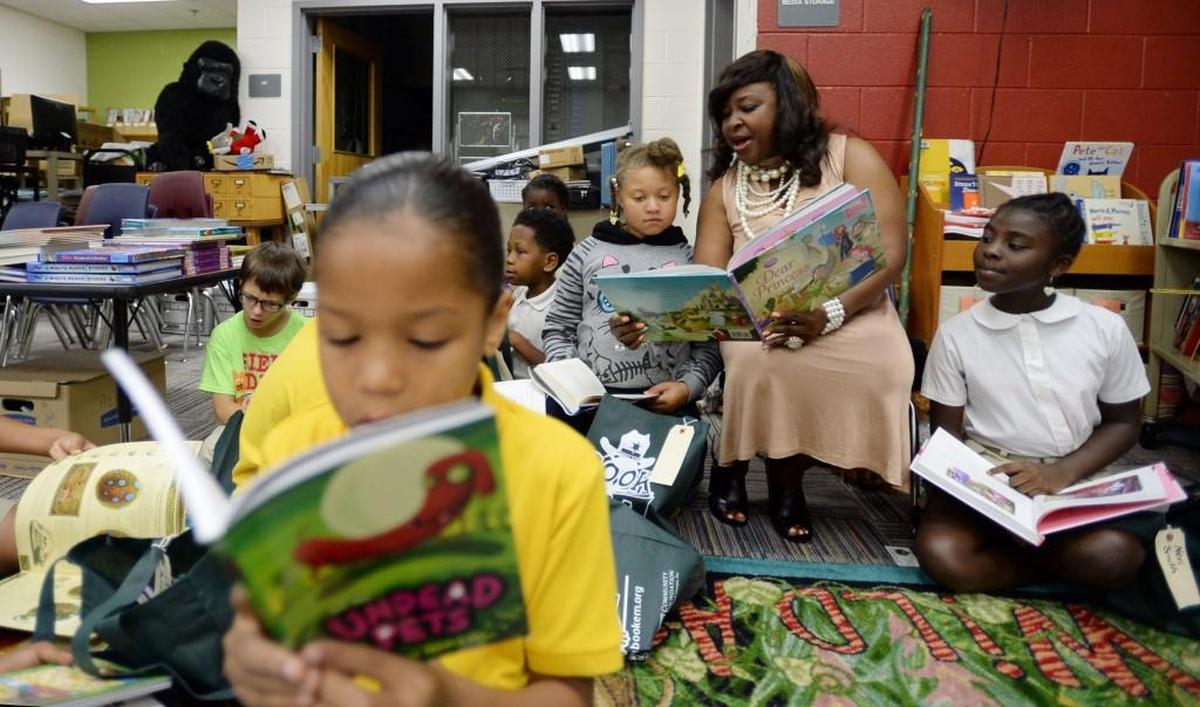 Brookdale third grade teacher Debra Shipp, at right, get immersed in the new books they picked out Thursday, gifts from Book `Em, to help the students with their summer reads.