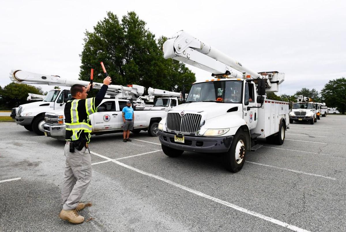 Jon Jaster directs utility trucks to their parking spaces at the Macon Centerplex Coliseum.