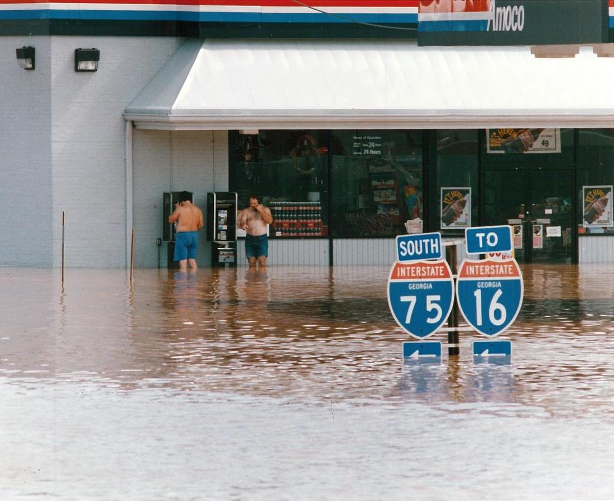 Two men use pay phones at a flooded Amoco gas station at the intersection of Riverside Drive and Pierce Avenue in Macon in July 1994.