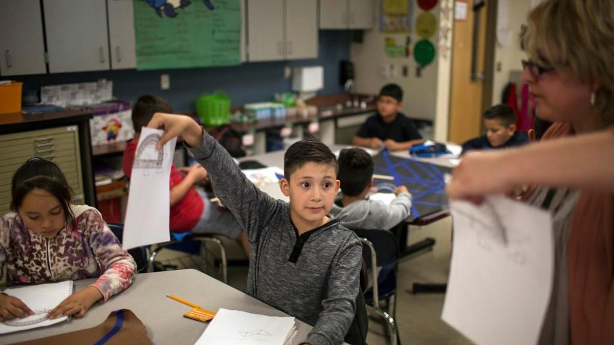 A fifth grade student shows his geometry work to a teacher at Columbus Elementary School, in Columbus, New Mexico, Friday, March 31, 2017. American kids living in Mexico make up about 60 percent of Columbus Elementary’s student body. Many are the children of parents who were deported and moved here to be able to send their kids to school in the United States.