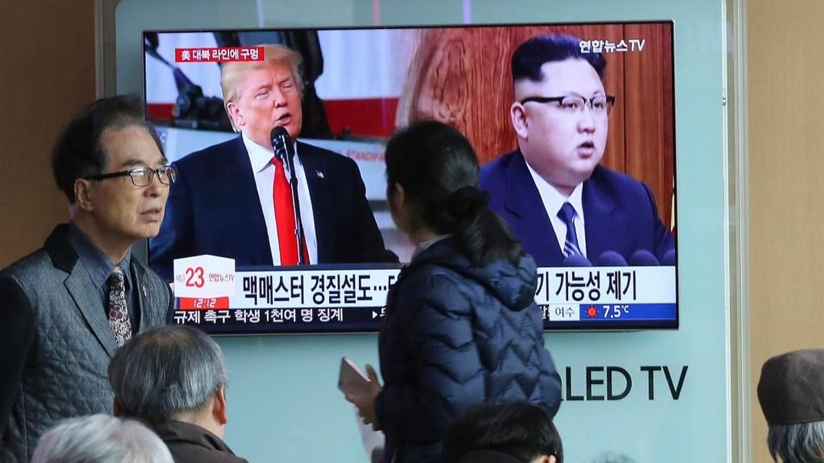 People pass by a TV screen showing North Korean leader Kim Jong Un, right, and U.S. President Donald Trump during a news program at the Seoul Railway Station in Seoul, South Korea, on March 17.