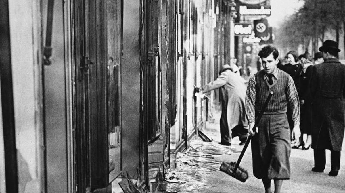 A young man with a broom clears broken glass from shop windows in Berlin, the morning after the Nazis demolished thousands of Jewish facilities during the night, in what was called "Crystal Night" later, Nov. 10, 1938.