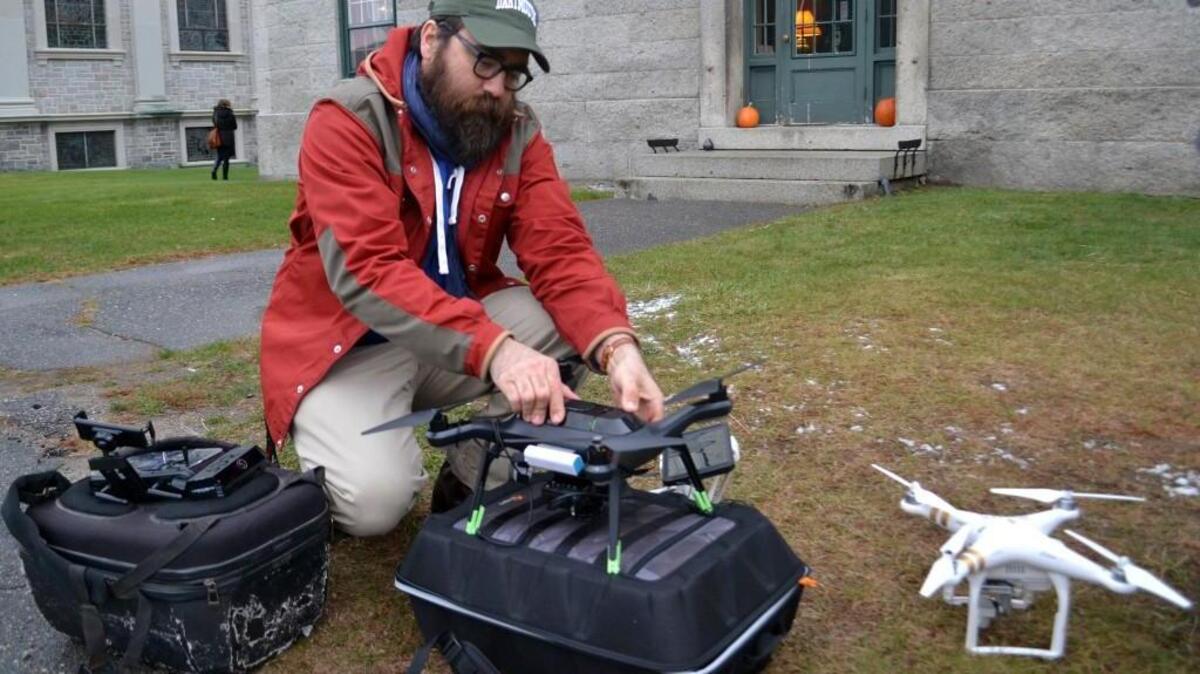 In this Nov. 14, 2017, photo, Dartmouth's Chad Hill readies a drone to be flown over a site of a Shaker Village in Enfield, NH. Hill and his Dartmouth colleague Jesse Casana are using drones equipped with thermal imaging cameras to study a half-dozen archaeological sites around the world. The cameras use heat differences between stone and the soil surrounding it to identify structures below the surface like foundations of buildings, which then can be further explored.