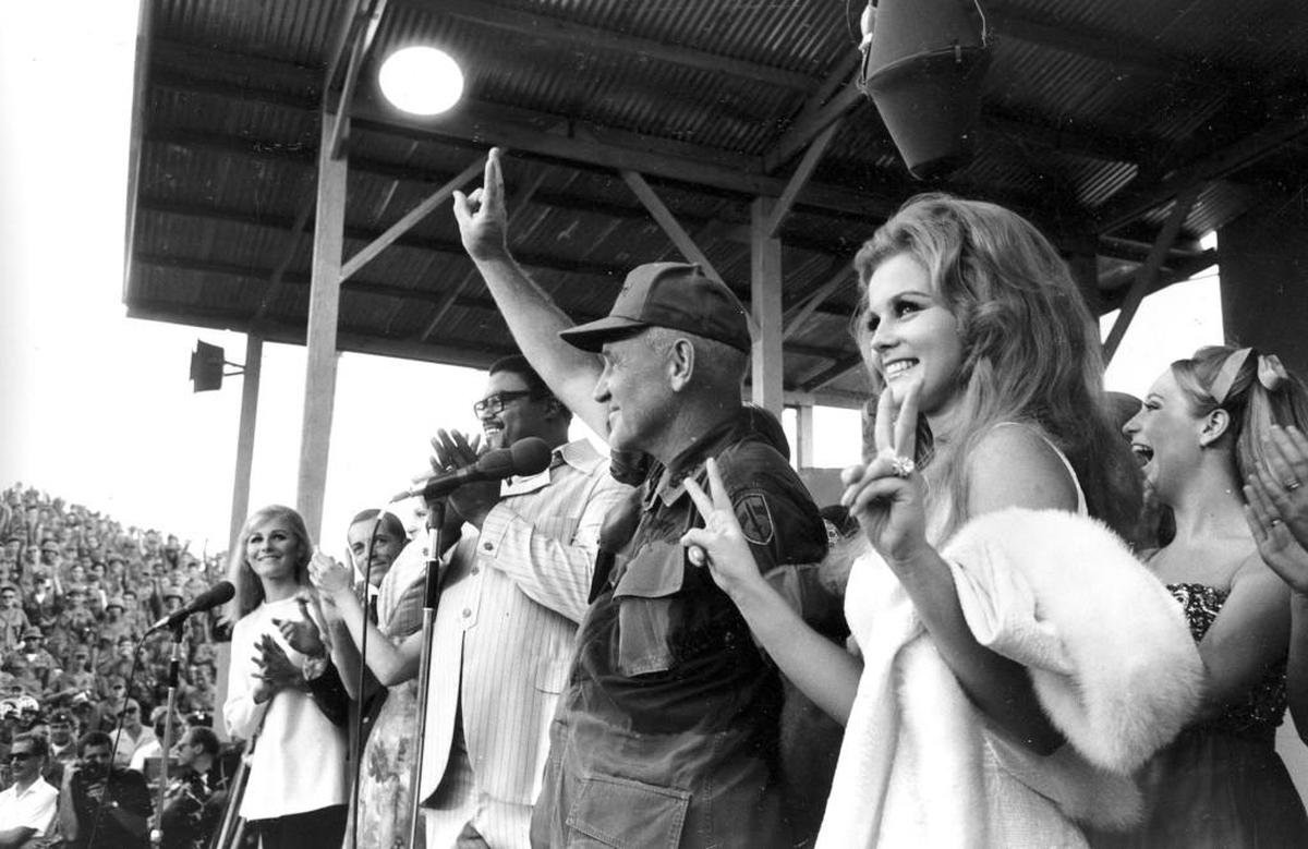 U.S. Sen. Creighton Abrahms, American Commander in Vietnam, and actress Ann-Margret give the "V" sign for Victory during the USO Bob Hope show in South Vietnam, Dec. 22, 1968. Looking on at far left in background is former football star Rosie Grier, who is accompanying Hope's Christmas tour.